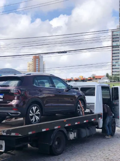 SUV vinho preso com cinta laranja na plataforma do guincho