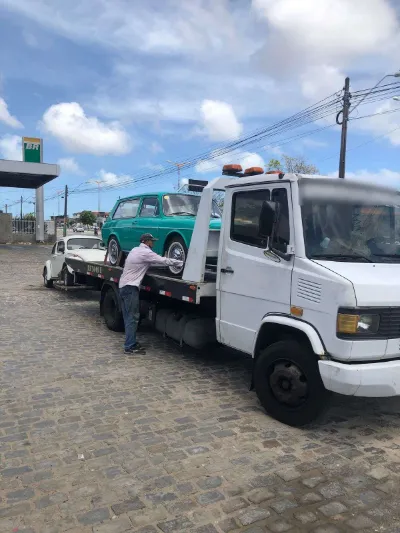 Operador prendendo uma Variant verde na plataforma, com um Fusca branco rebocado atrás